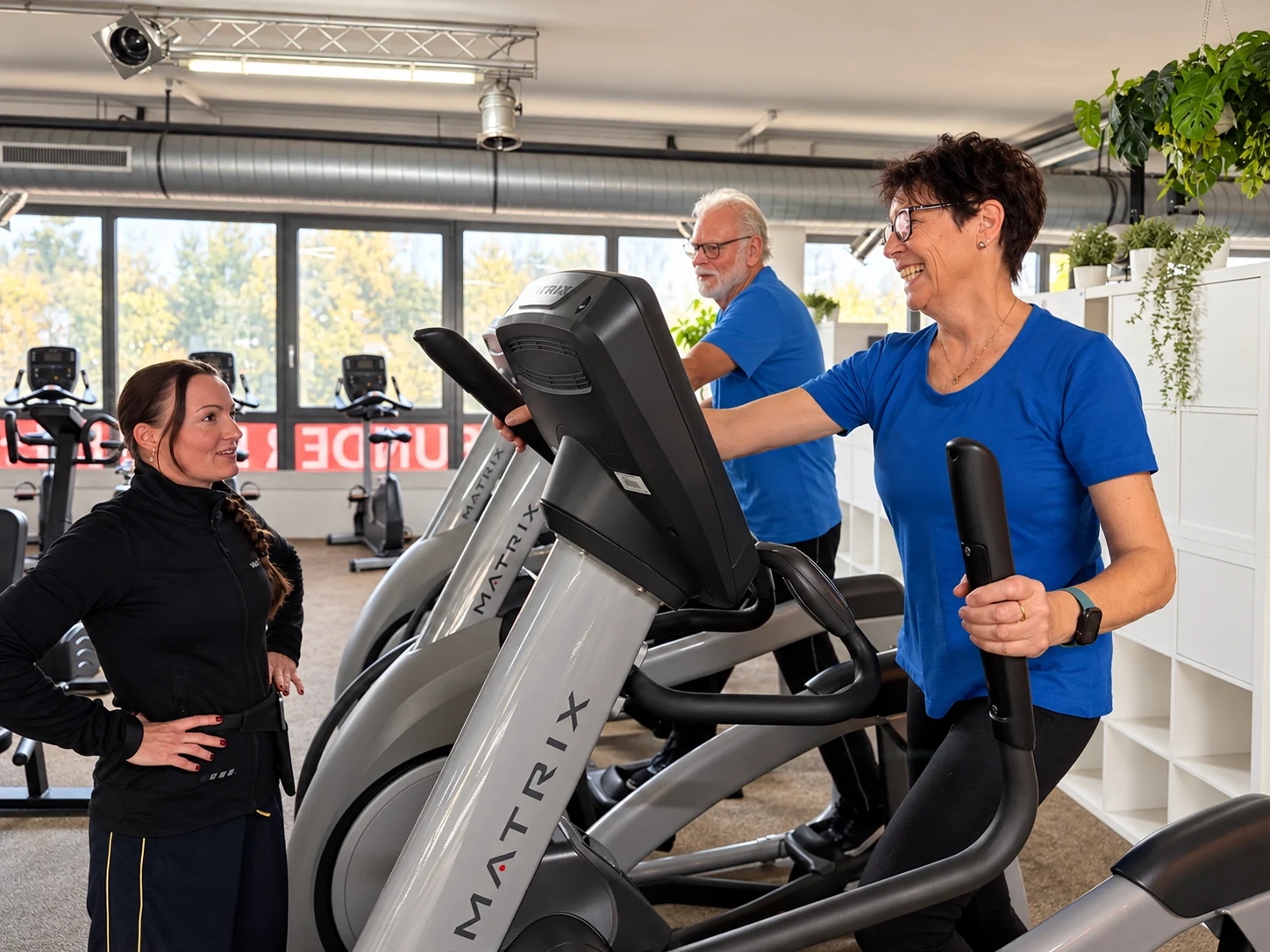 Ältere Trainierende an Cardiogeräten mit einer Trainerin im Gesundheitsstudio Wolff