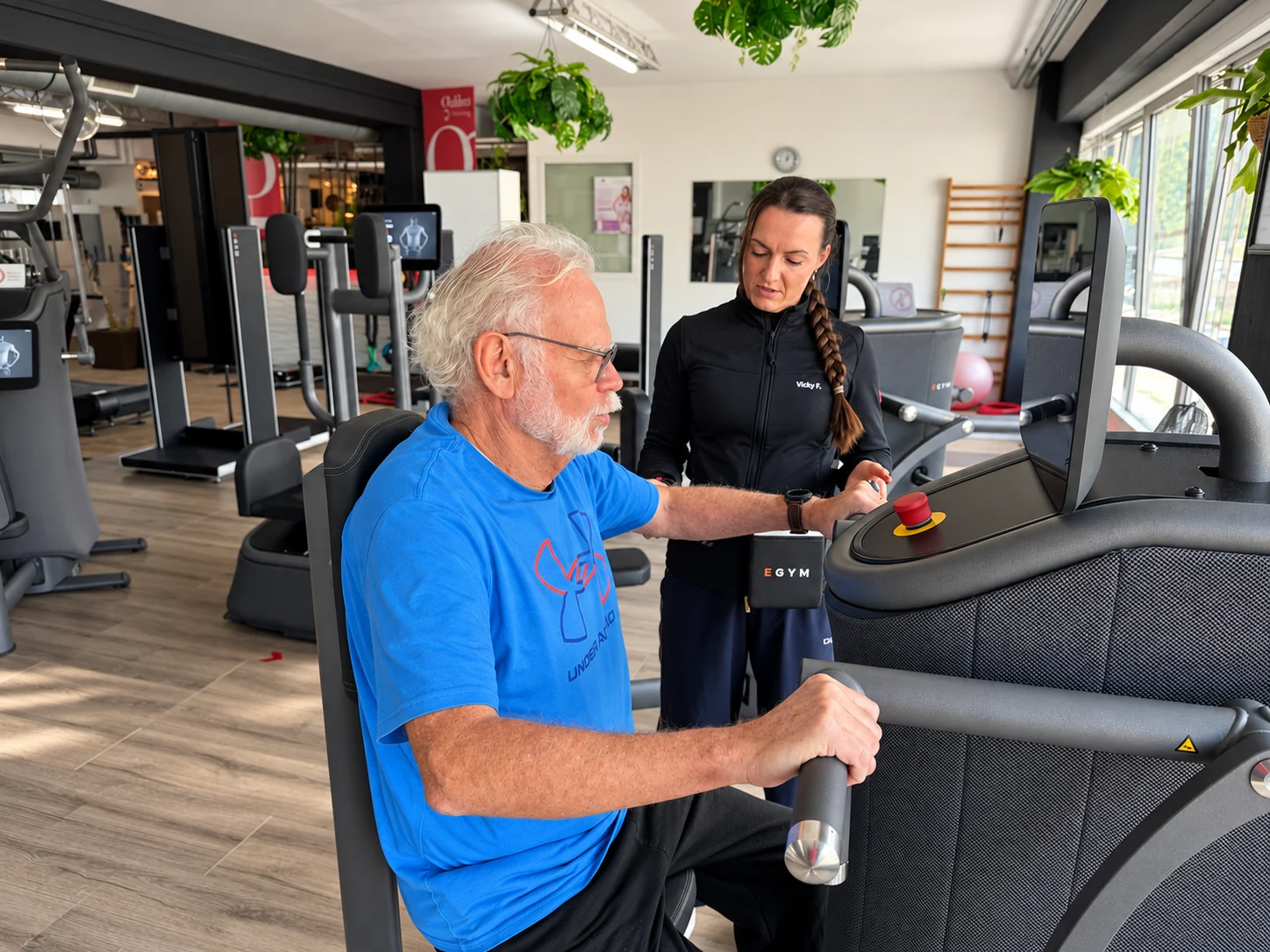 Trainerin begleitet einen älteren Trainierenden beim Gerätetraining im Gesundheitsstudio Wolff